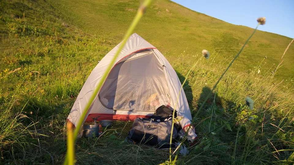 Kleines Zelt auf einer sonnigen Wiese als Sinnbild für Camping unterwegs